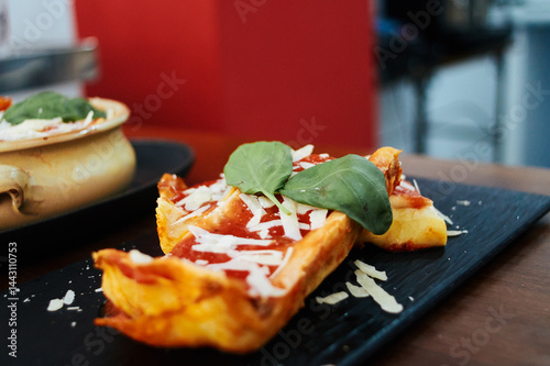 Obraz na płótnie A plate of food with cheese and basil on top. The plate is on a table. There is a bowl of food on the table as well w salonie