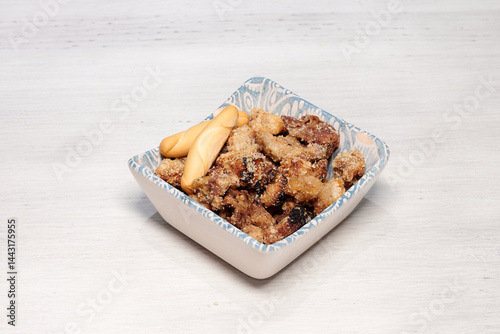 A bowl of food with a piece of bread and a fork. The food is in the shape of a square