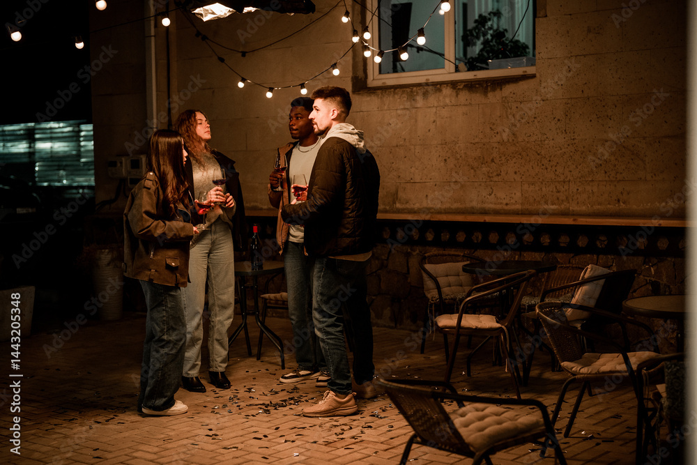 Obraz premium Friends enjoy an evening gathering outdoors under fairy lights in a lively atmosphere