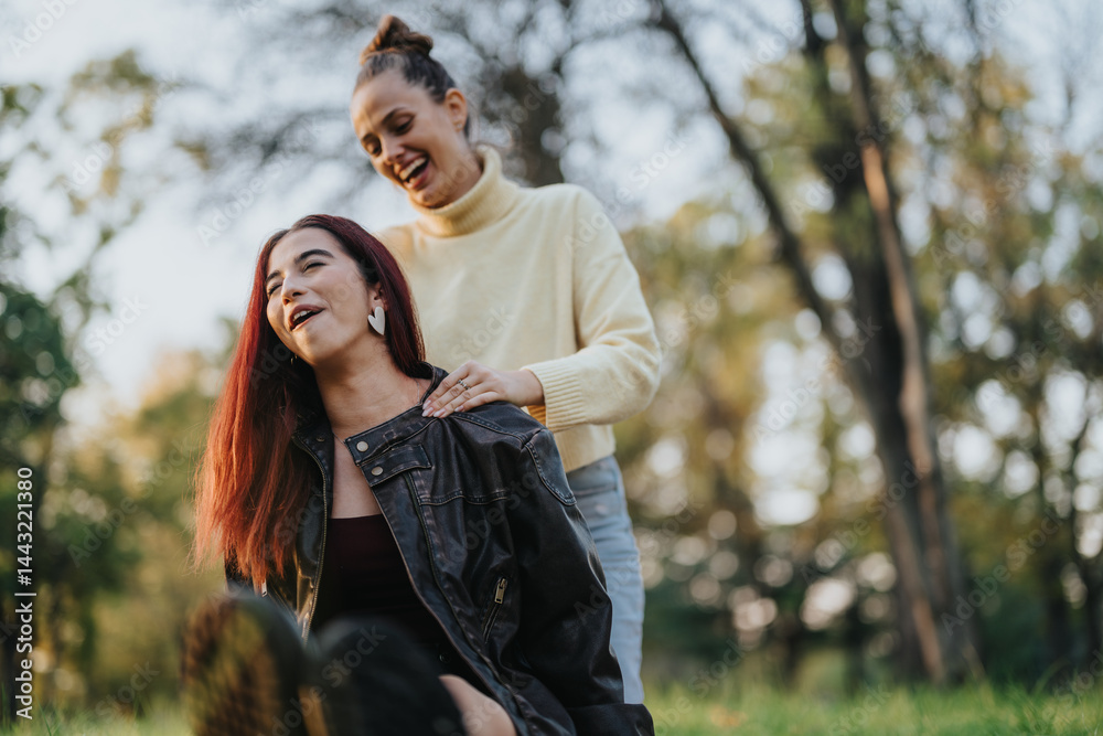 Fototapeta premium Two women are depicted having fun and laughing together in a tranquil park setting, enjoying the serene beauty of nature and cheerful company.