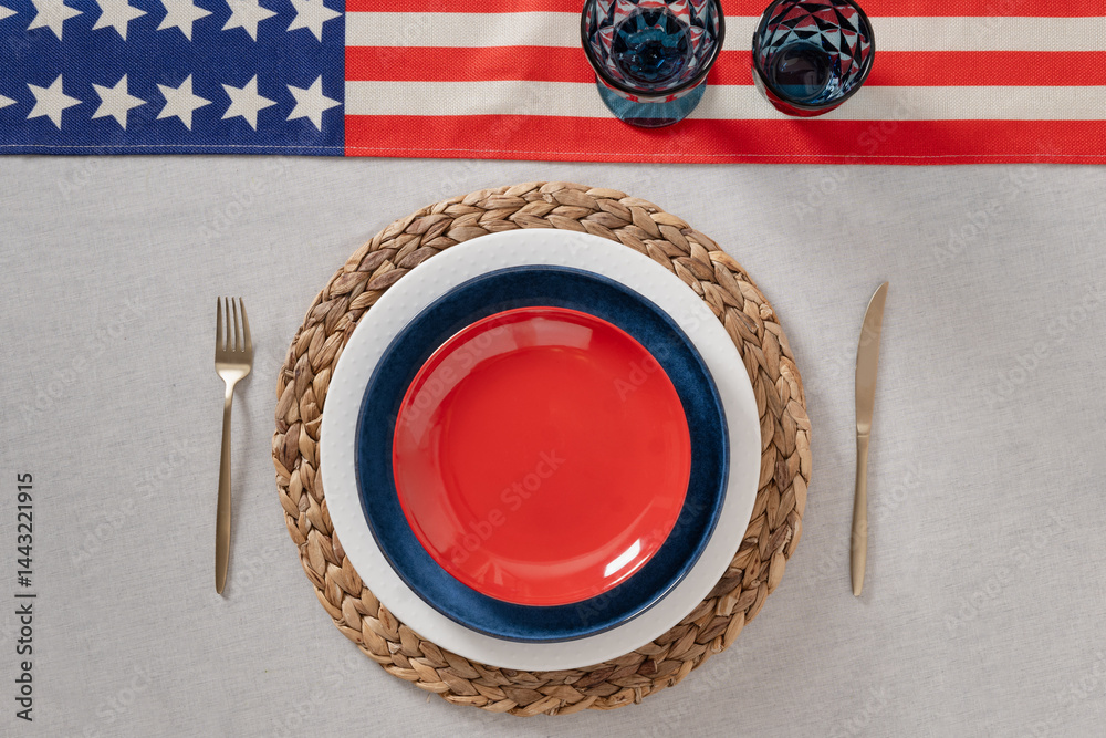 Patriotic table setting for USA Independence Day. Festive dinner with empty red plate and decoration in USA national flag colors white, red and blue. View from above. Copy space.