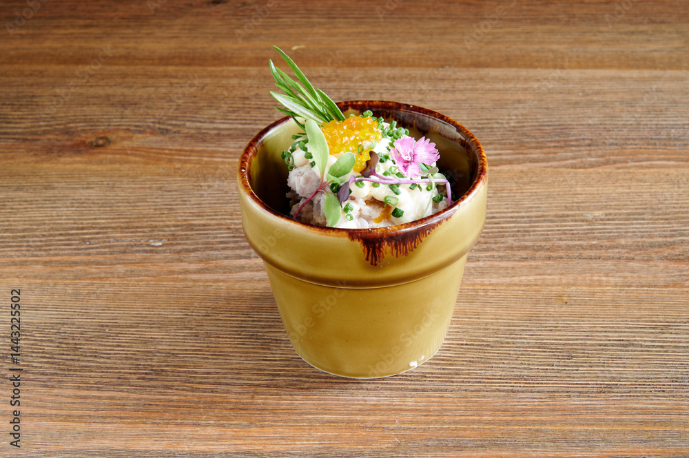 A small bowl of food with a flower on top. The bowl is brown and has a green stem