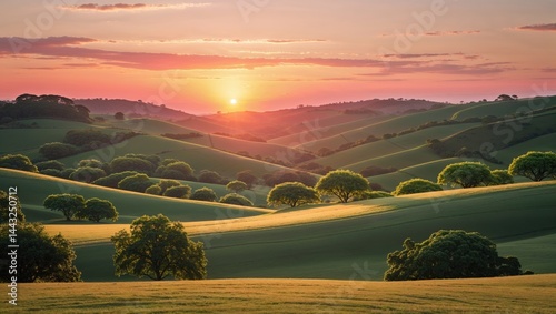 Serene sunset over rolling green hills. The warm glow of the setting sun casts long shadows across the landscape, creating a picturesque scene.