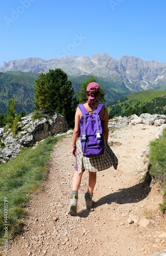 Obraz na płótnie female hiker with backpack walking on dirt trail in mountains w salonie