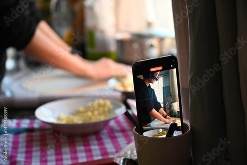Obraz na płótnie Filming on a phone as a girl cooks pizza. Home shooting. Video content for social networks. w salonie