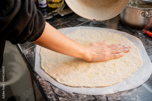 Obraz na płótnie Close-up scene of female hands applying white sauce to dough on kitchen countertop. Making homemade pizza with three types of cheese - female hands in action. w salonie