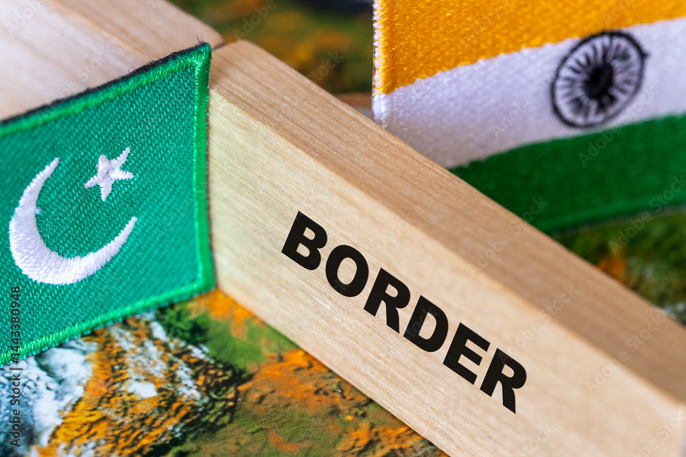 Pakistan-India border. Flags of India and Pakistan and a wooden block border symbol dividing the two countries. close up