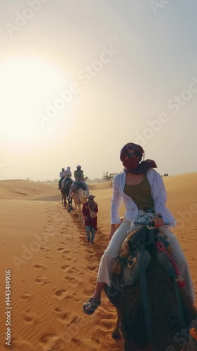 Travelers riding camels through stunning desert dunes on an adventurous safari, vertical video