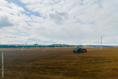 Spring autumn season countryside works.Harvesting farming wheat.Agricultural vehicle machine tractor is working on plowed field on sunny daytime.