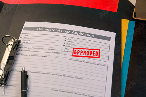 Commercial loan application with approved stamp on desk