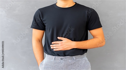 Person with hand on stomach, possibly in discomfort or indicating stomachache. Grey background