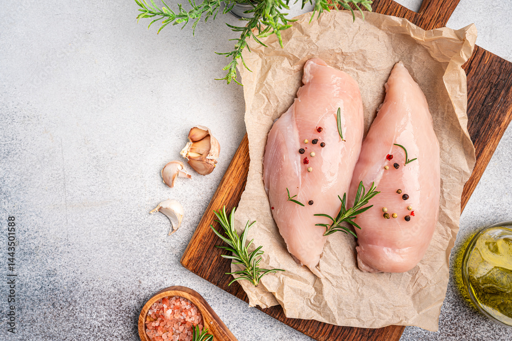 Raw chicken fillet or breasts with ingredients for cooking on a paper, gray background. Top view with copy space. High quality photo