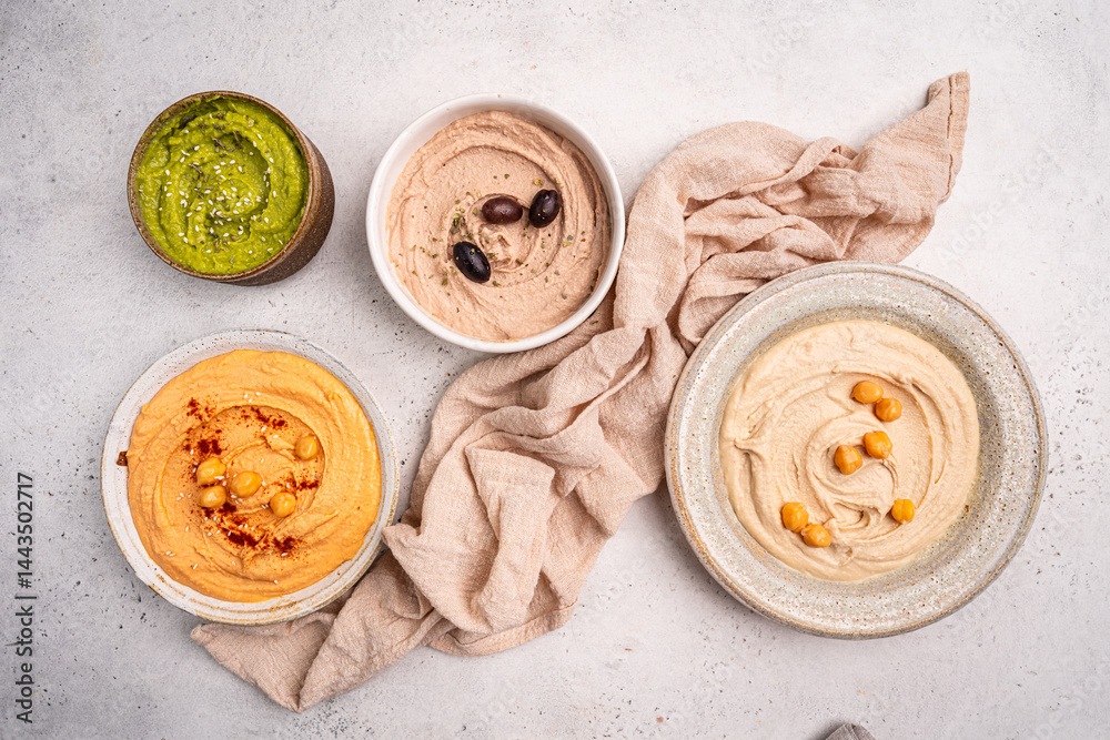 Various hummus dips in different colours. Hummus with dry crackers, top view. Vegan and traditional hummus as healthy and vegan snack.