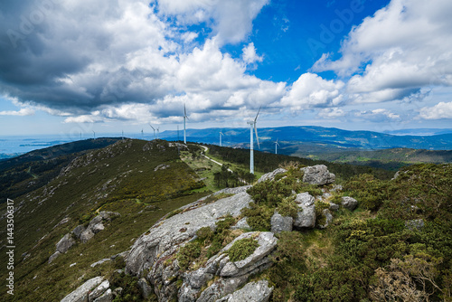 Wind turbines generating clean energy on mountain ridge under cloudy sky
