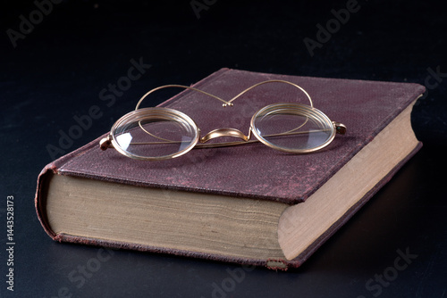 Occhiali da lettura su un vecchio libro su sfondo nero