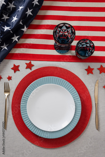 Table setting for USA Independence Day. Festive dinner with plate and decoration in USA national flag colors and stars. Vertical. View from above