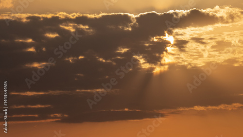 aerial view to clouds and sun behind with beams and orange colours with copy space