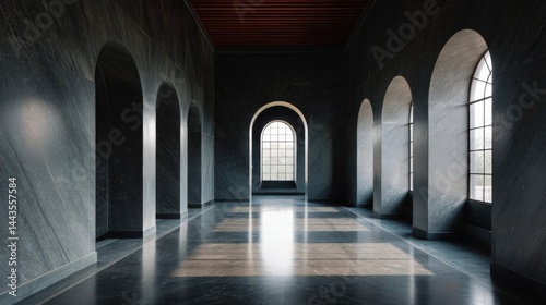 Long, empty room with a high ceiling and arched windows on the right side. the walls are made of dark grey stone and the floor is made of marble tiles.