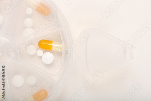Obraz na płótnie A close-up shows a section of a clear plastic pill organizer containing various white round pills and yellow and white capsules w salonie