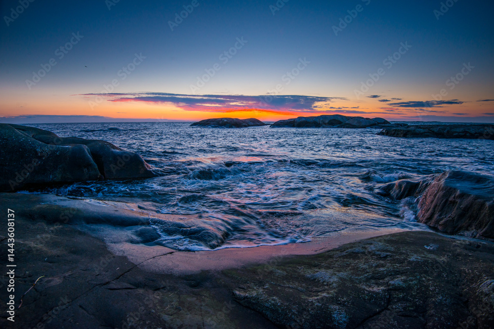 Dramatic coastal sunset over rocky shore.