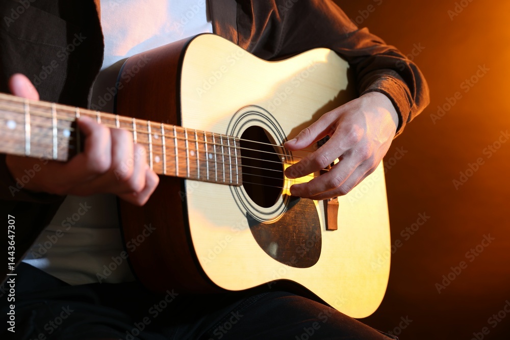 Fototapeta premium Man playing guitar on brown background, closeup
