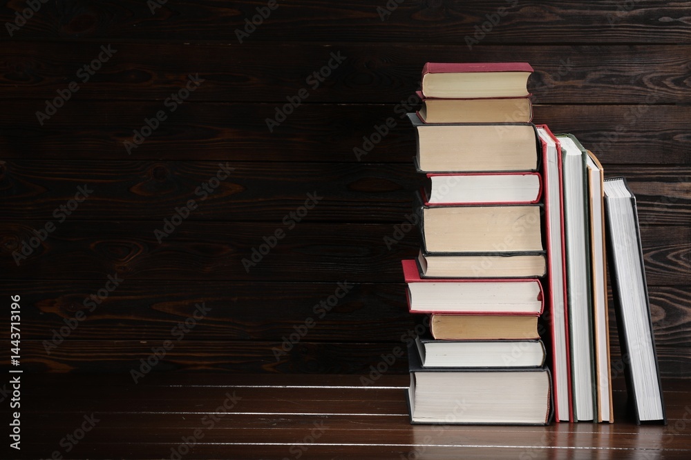 Fototapeta premium Stack of old books on wooden table, space for text