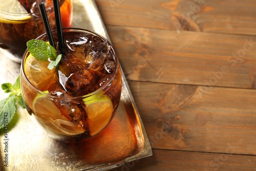 Refreshing Cuba libre cocktail with mint on wooden table, closeup. Space for text