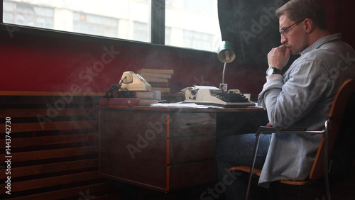 Soft-focused image of a male novelist experiencing creative frustration at his home office desk.