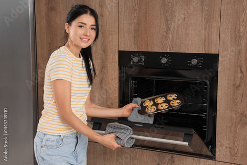 Young woman putting baking ...