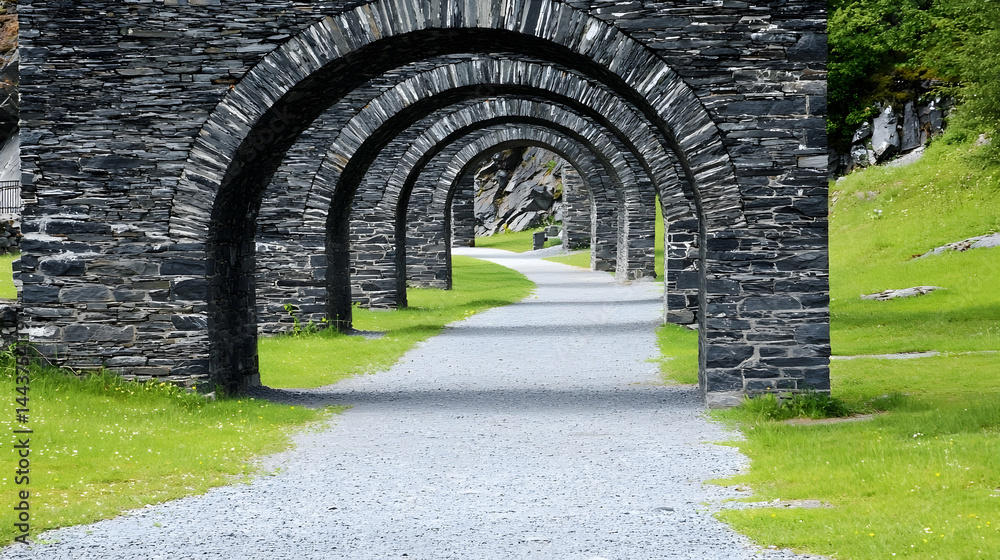 Fototapeta premium Stone archway path, mountain landscape, gravel trail, scenic walkway, nature background, ideal for travel brochures