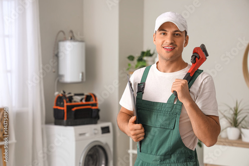 Male plumber with wrench and clipboard in bathroom