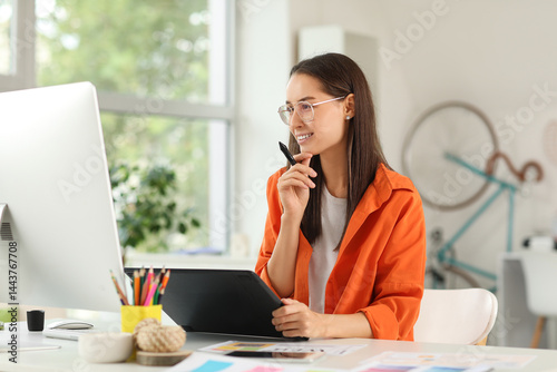 Obraz na płótnie Thoughtful young female graphic designer with tablet sitting at table in office w salonie