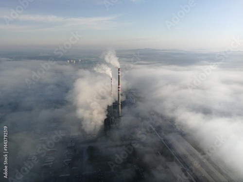 Aerial view of factory chimney emitting smoke above fog layers during temperature inversion, concept of air pollution. photo