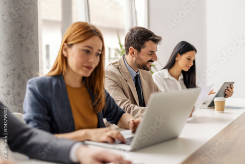 Happy executive sitting at boardroom with his team and working on project.