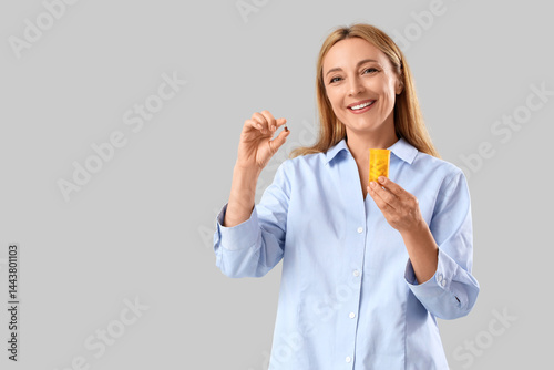 Mature woman with pills on light background. Homeopathy concept
