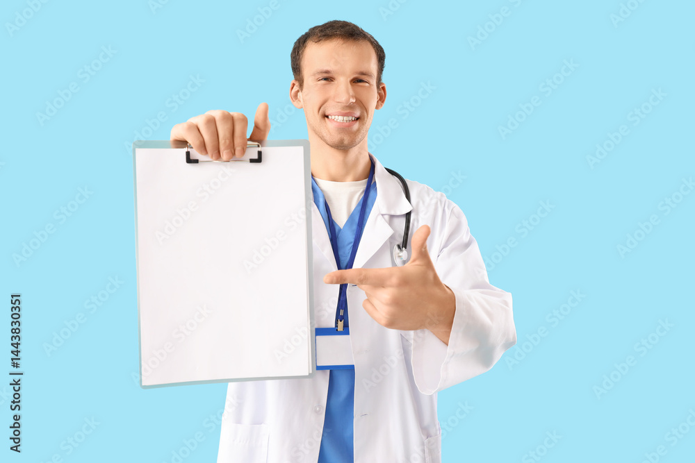 Male doctor pointing at blank clipboard on blue background Male doctor pointing at blank clipboard on blue background