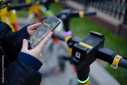 Obraz na płótnie Scanning by smartphone QR code of kicksharing system electric scooters on city street at daytime. Shallow depth of field w salonie