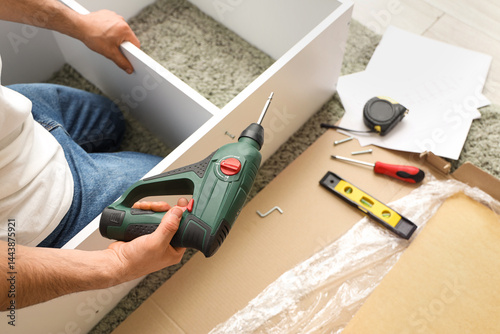 Wallpaper Mural Young man with drill assembling shelf unit at home, top view Torontodigital.ca