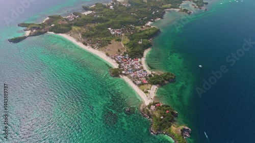 Aerial view of Malapascua Island in the Philippines, featuring vibrant turquoise waters, lush tropical vegetation, and colorful houses along the picturesque coastline