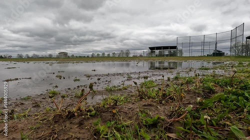 Flooded Baseball Field. Game cancelled! Empty baseball field in a public park setting. The field has been flooded with water following rainfall. Overcast cloudy skies above.