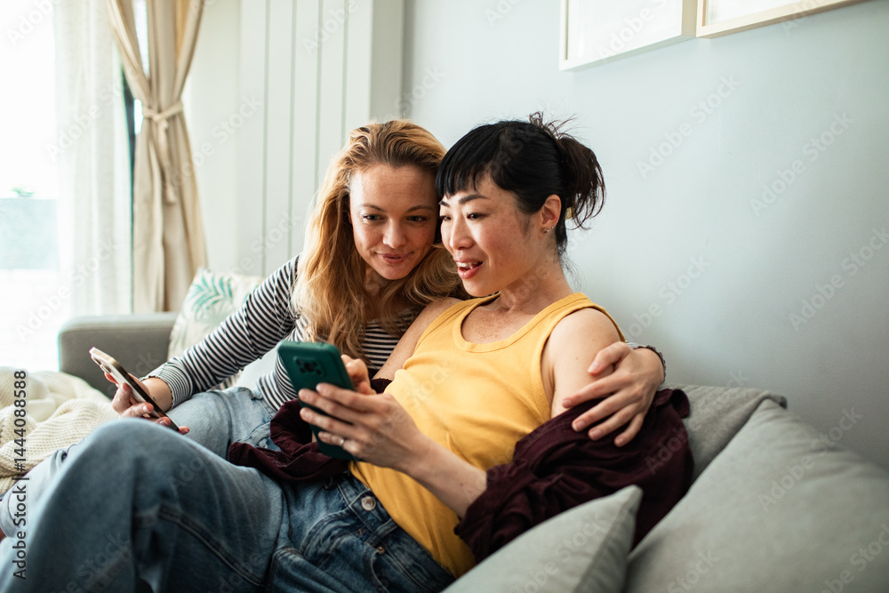 Lesbian couple relaxing on the couch with smartphones at home