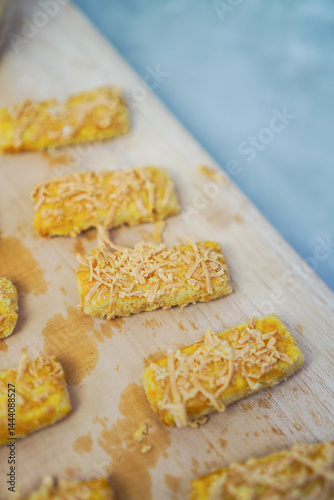 cheese cookies lined up on a wooden chopping board