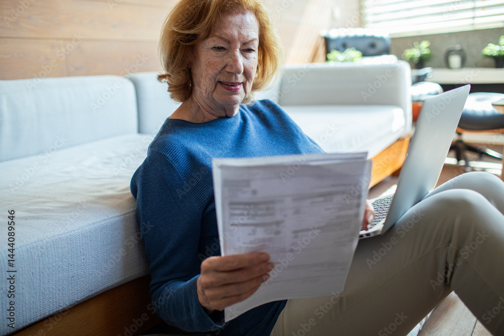Senior woman managing finances online with laptop at home