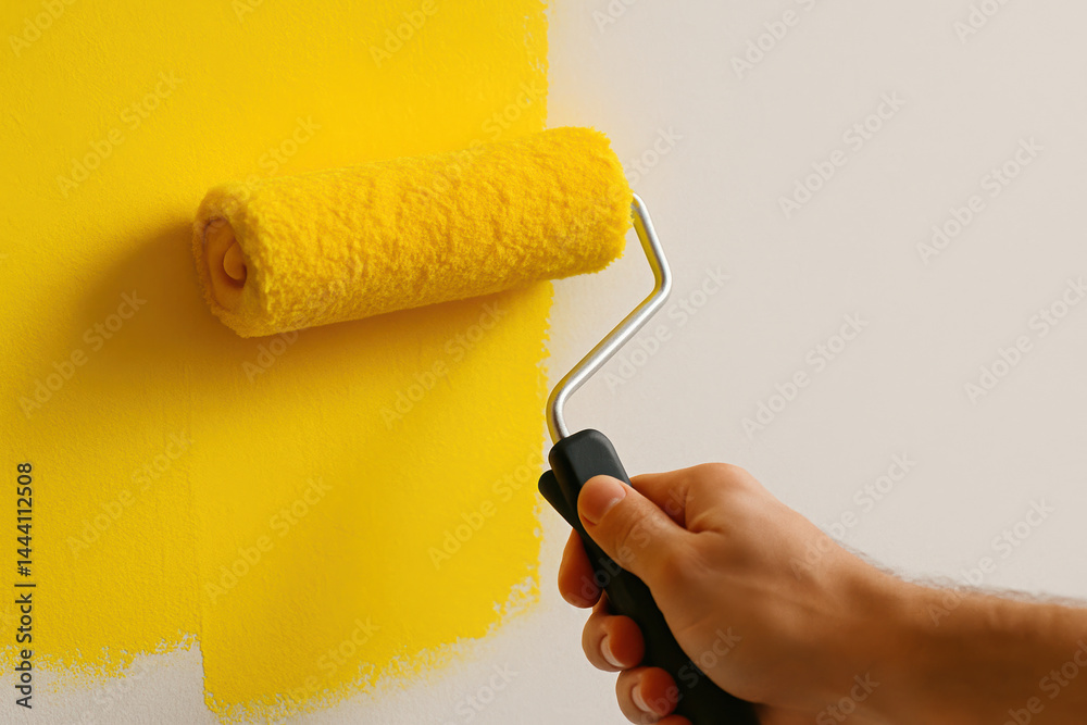 Obraz premium Person painting wall with yellow roller for a fresh, vibrant makeover
