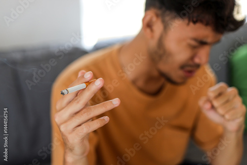 Bild auf Leinwand Man having a severe cough while smoking a cigarette at home