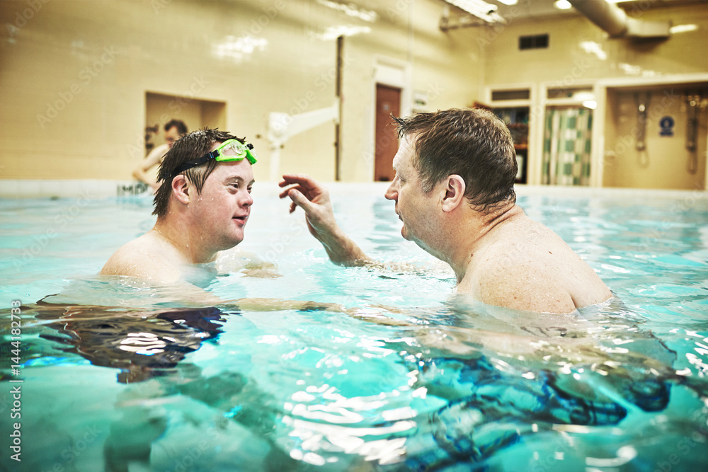 Fototapeta premium Pool, disability and down syndrome man in swimming class for exercise, mental and physical development in water. Fitness, workout and disabled person learning to swim and float at special home