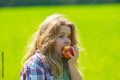 Obraz na płótnie The child boy eats an apple. Ripe fruit for kids. Child bites apple. The child boy eat healthy food. A kid holds apple. Summer sun. Child takes bite of apple. Fresh apples for kids healthy snack. w salonie