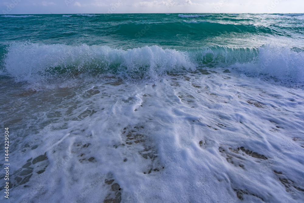 Turquoise water wave motion. Summer beach. Calm beach. Luxury seaside resort. Bright sky and waves on the beach. Beautiful foamy shoreline. Sea background. Blue ocean. Sandy beach.