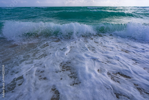 Obraz na płótnie Turquoise water wave motion. Summer beach. Calm beach. Luxury seaside resort. Bright sky and waves on the beach. Beautiful foamy shoreline. Sea background. Blue ocean. Sandy beach. w salonie