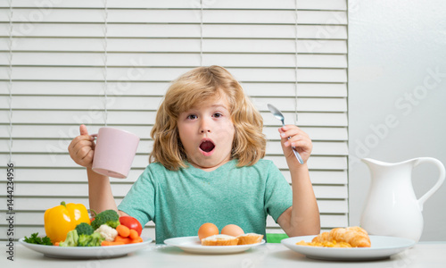 Funny kid boy having breakfast. Milk, vegetables and fruits healthy food nutrition for children.